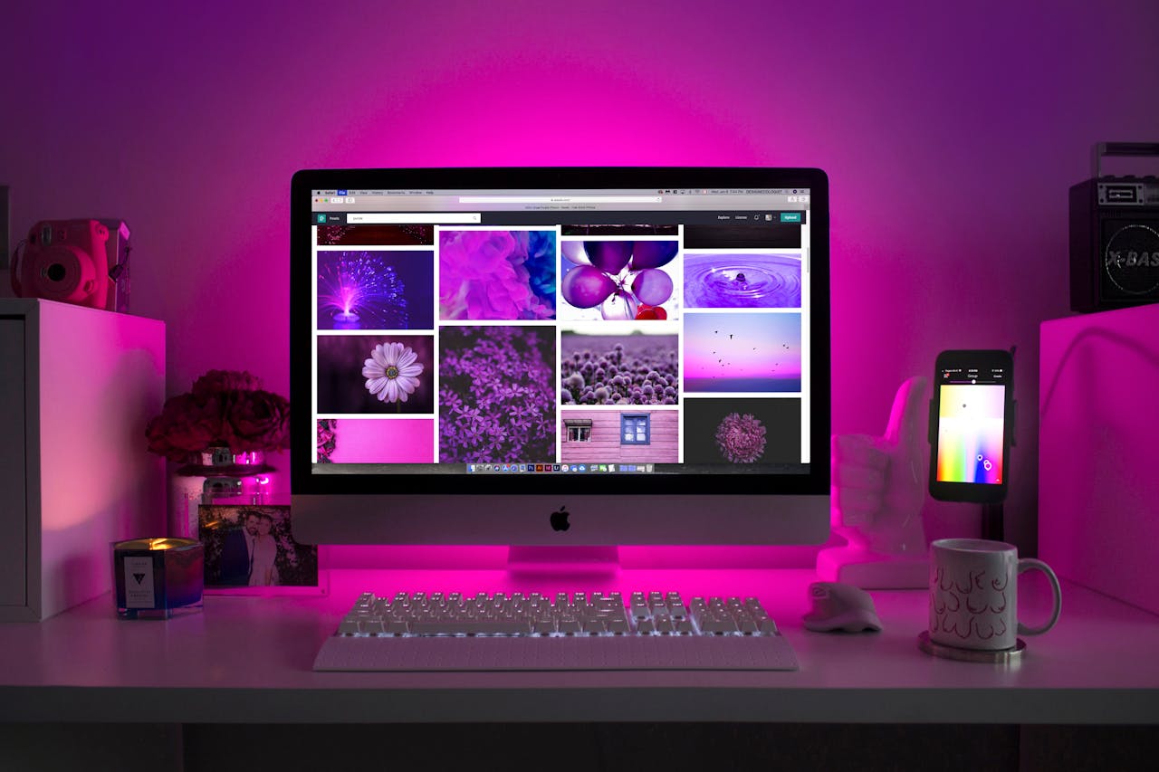 Home Modern desk setup with neon lighting and a desktop computer displaying colorful images.